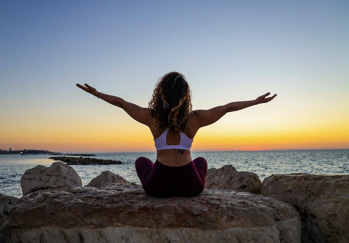 Person stretching by the water at sunset